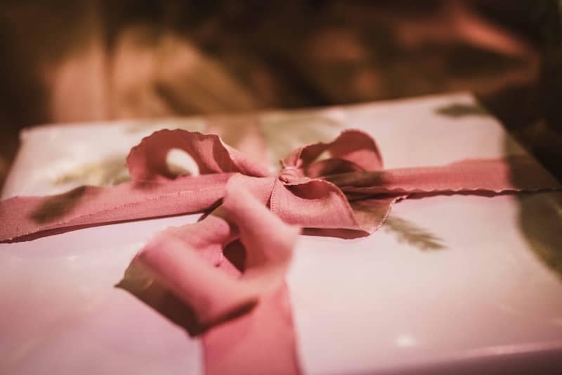 A hand tying a ribbon on a gift box